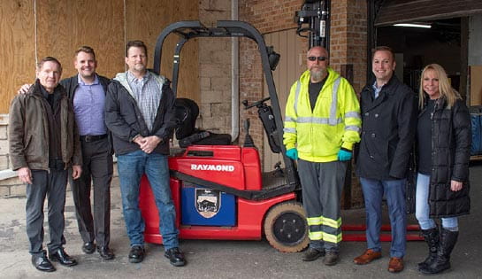 Three Associated employee and three Hesed House staff take a photo by the donated forklift